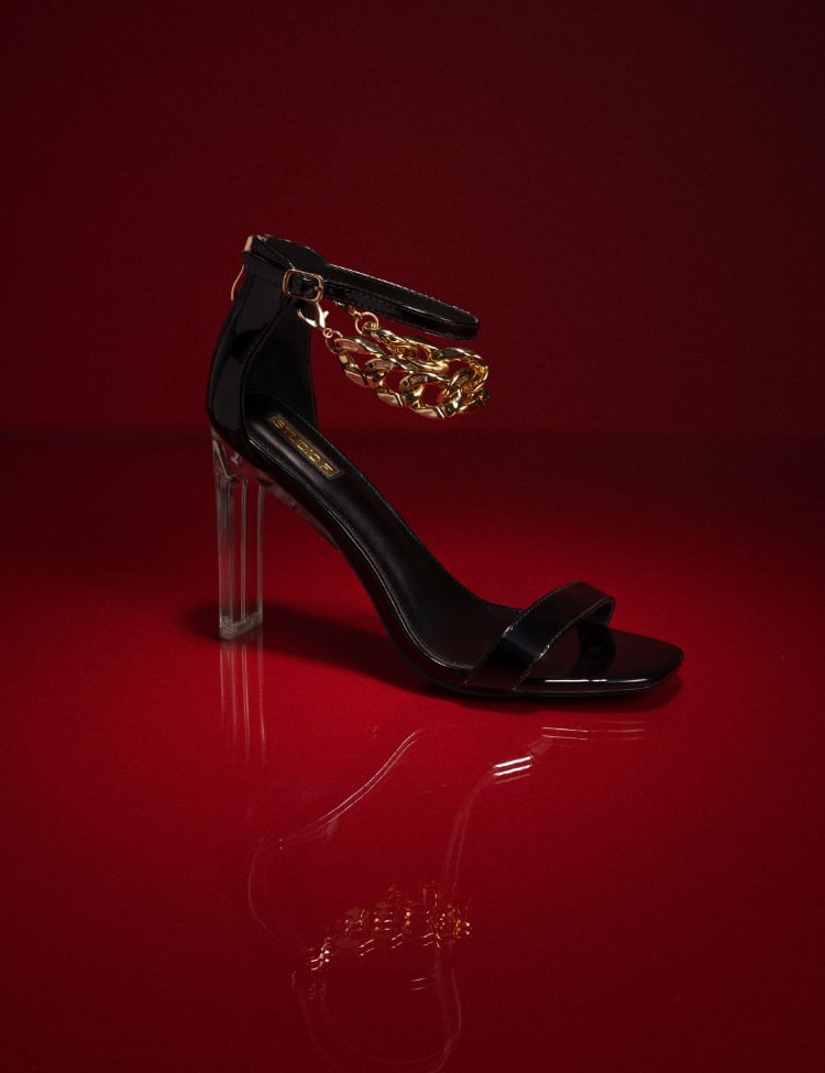 Sandalia negra con tacón transparente y cadena dorada de la campaña San Valentín, Studio F 