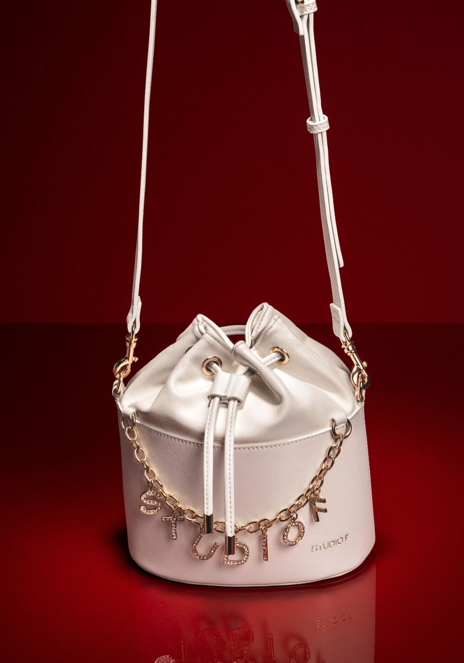 Bolso manos libres para mujer de color blanco con cadena y letras doradas. Campaña San Valentín, Studio F 