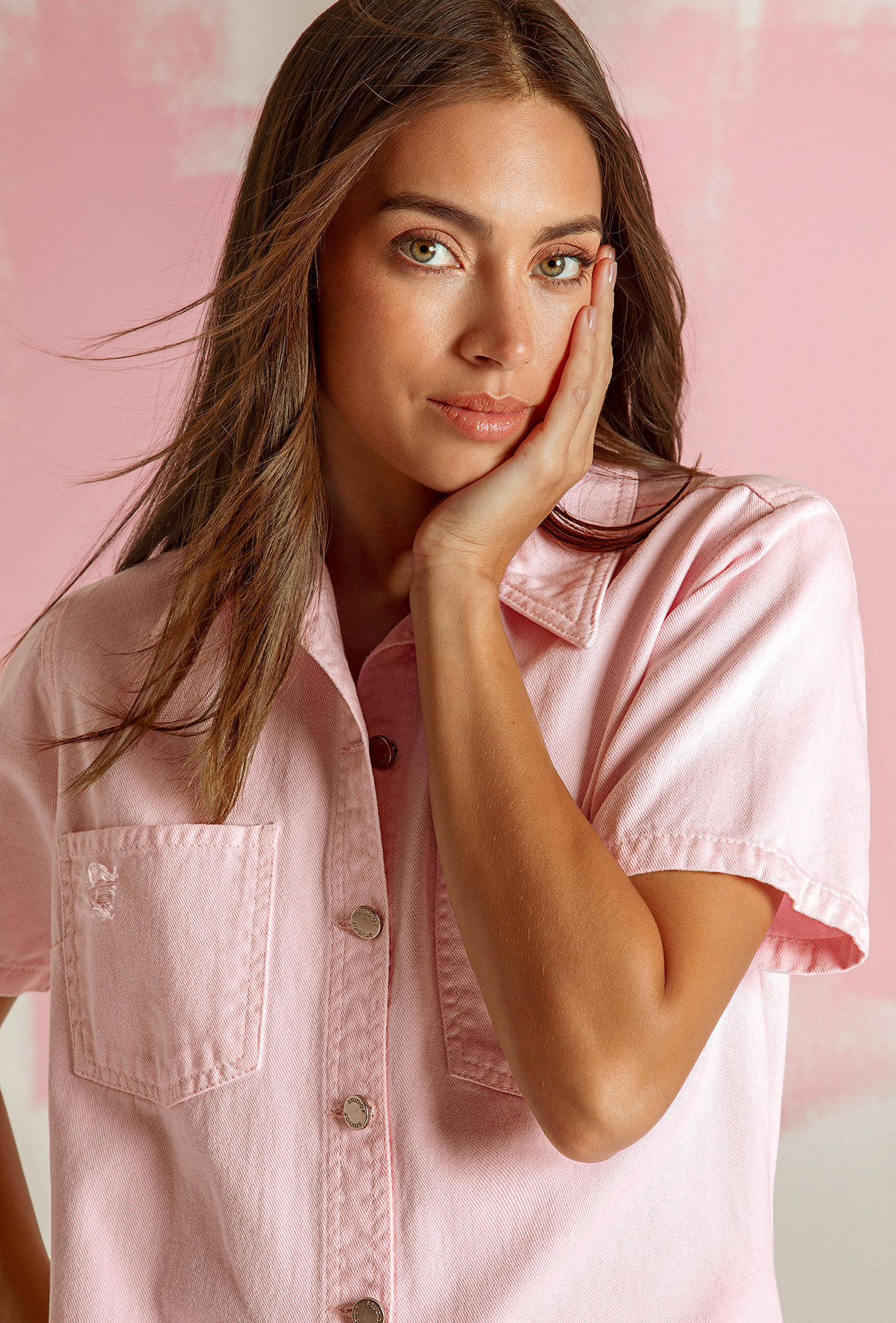 Foto de Laura Archbold usando blusa rosa con manga corta, botones plateados y bolsillos frontales
